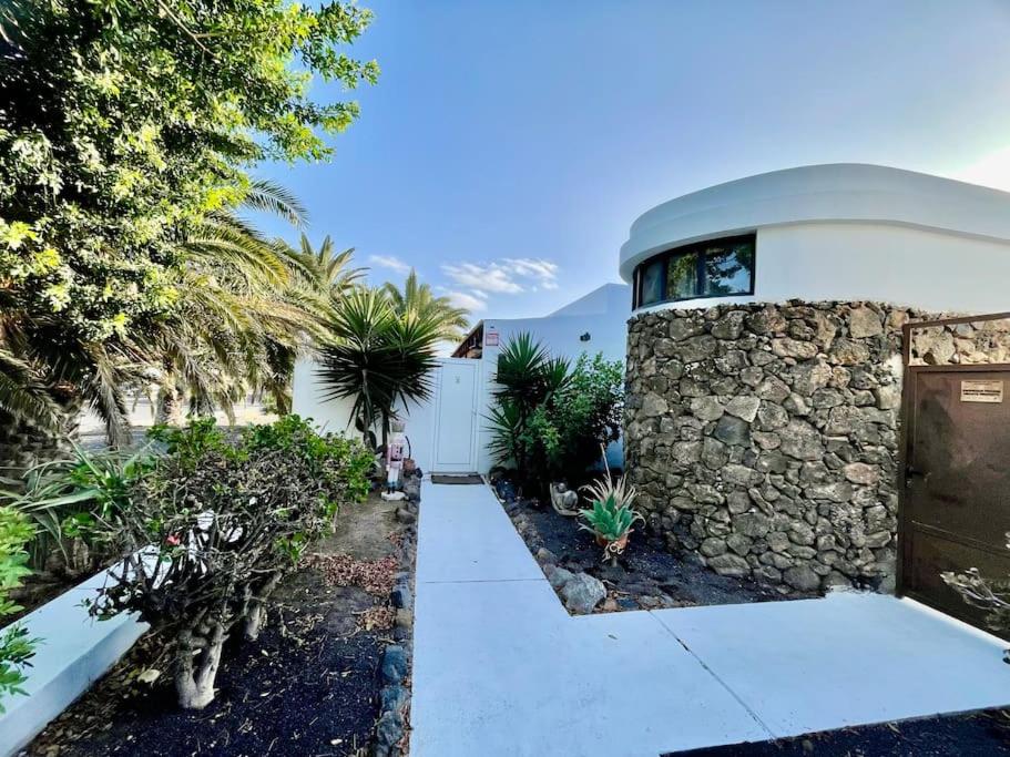 una casa con una pared de piedra y un camino de entrada en Oasis en Lanzarote, en Costa Teguise