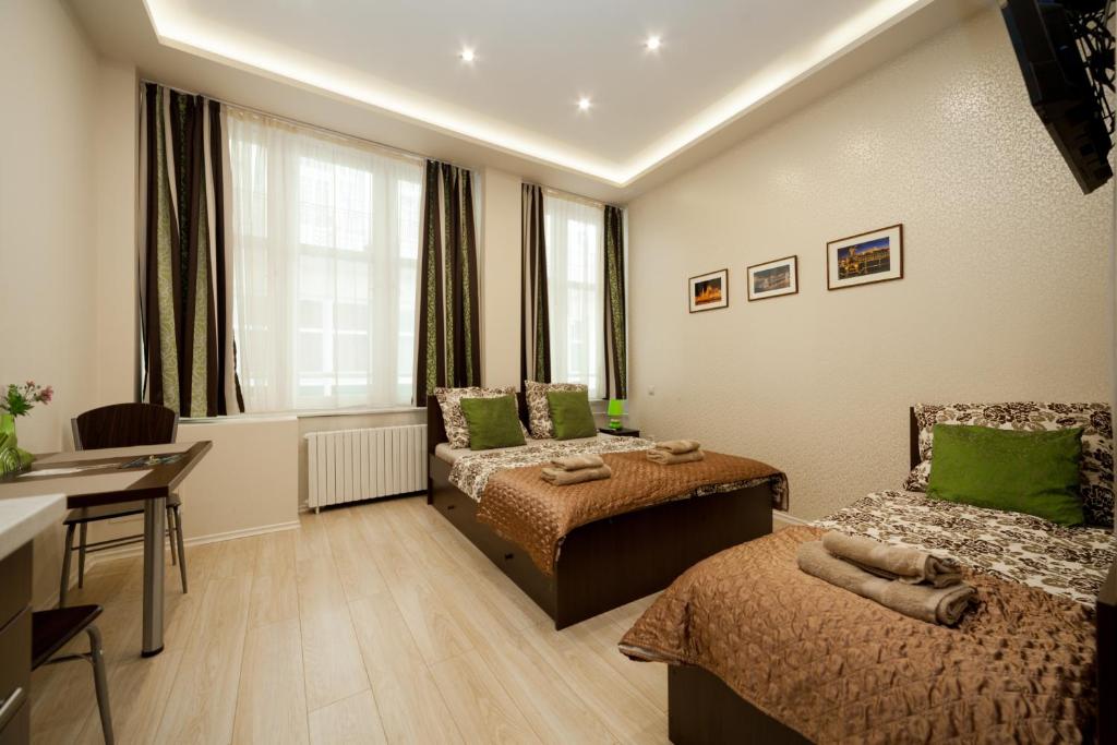 Cette chambre comprend deux lits, une table et un bureau. dans l'établissement Budapest Holidays Apartments, à Budapest