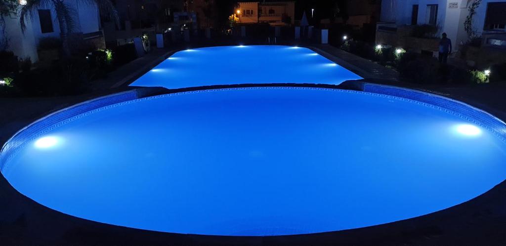 a large pool with blue illumination at night at Appart. 4pc à 150m², vue mer et pieds dans léau in Oued Laou