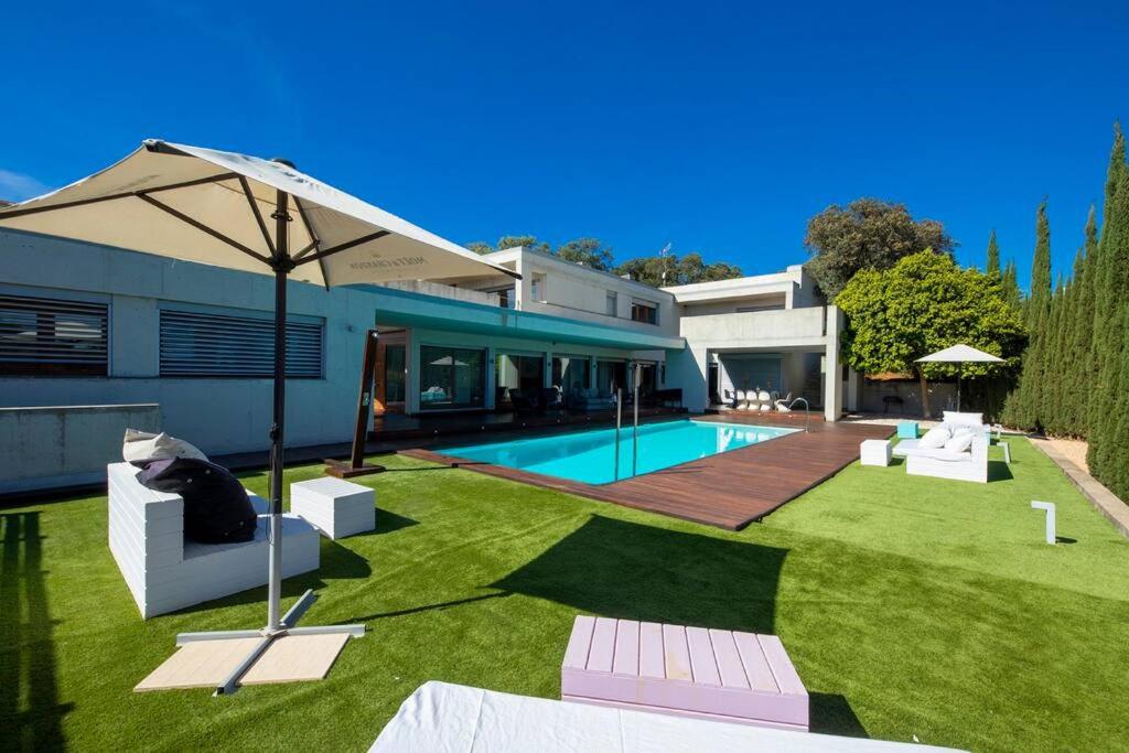 een huis met een tuin met een zwembad en een parasol bij La villa de Berlín en Sevilla in Guillena