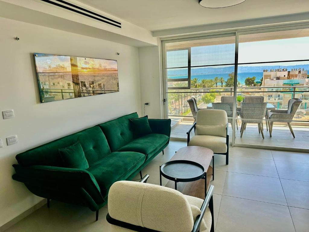 sala de estar con sofá verde y sillas en Suite In White, en Acre