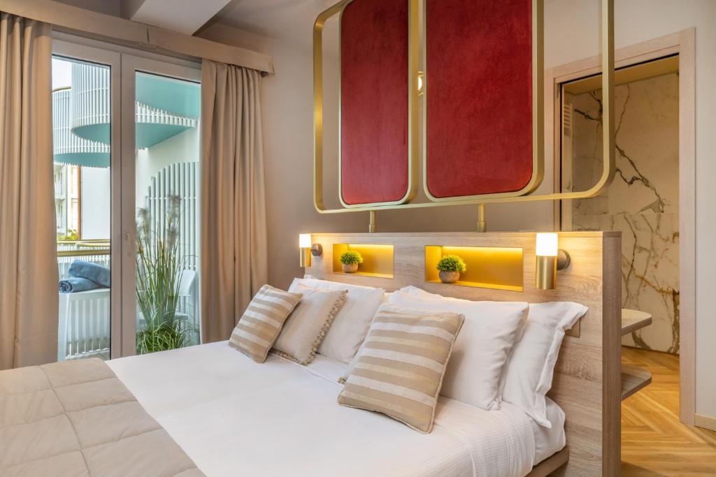 ein Schlafzimmer mit einem weißen Bett mit Spiegeln darüber in der Unterkunft Salus Smart & Chic Hotel in Lido di Jesolo