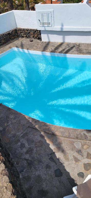 Una piscina de agua azul con un banco. en Casa Moja - La Palma, en Tazacorte