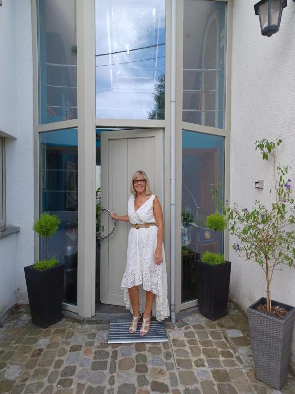 a woman standing in the doorway of a building at B&B La maison de Régine in Jalhay