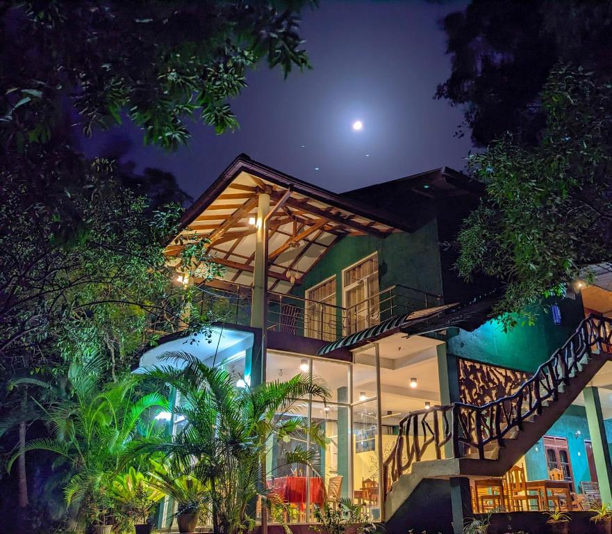 a house at night with the moon in the sky at Choona Lodge 'view of sigiriya & pidurangala with sunrise' in Sigiriya