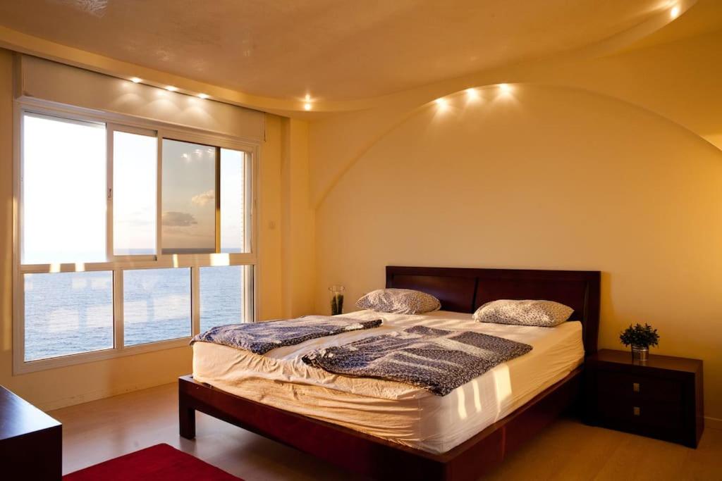 a bedroom with a bed with a large window at Nitza Seaview Apartments in Netanya