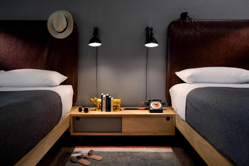1 dormitorio con 2 camas y mesita de noche entre ellas en MOXY Phoenix Tempe/ASU Area, en Tempe
