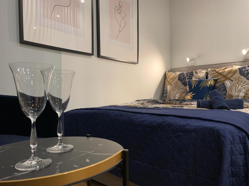 twee wijnglazen op een tafel naast een bed bij Indygo Apartment in Krakau