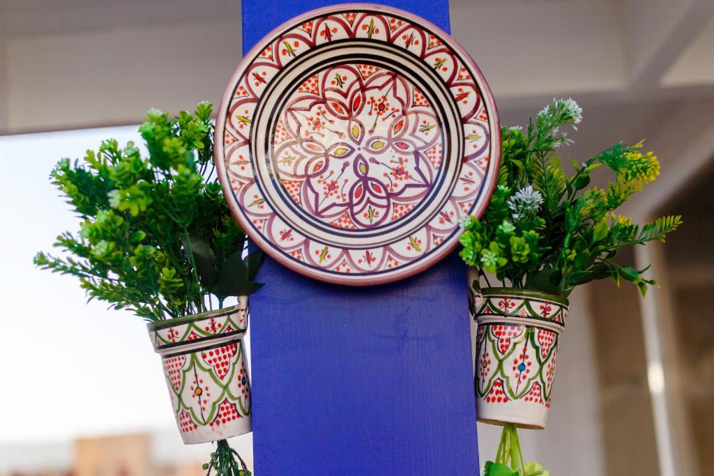 a plate on a pole with two potted plants at The Rina Hostel in Agadir