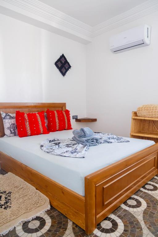 a bedroom with a wooden bed with red pillows at The Rina Hostel in Agadir