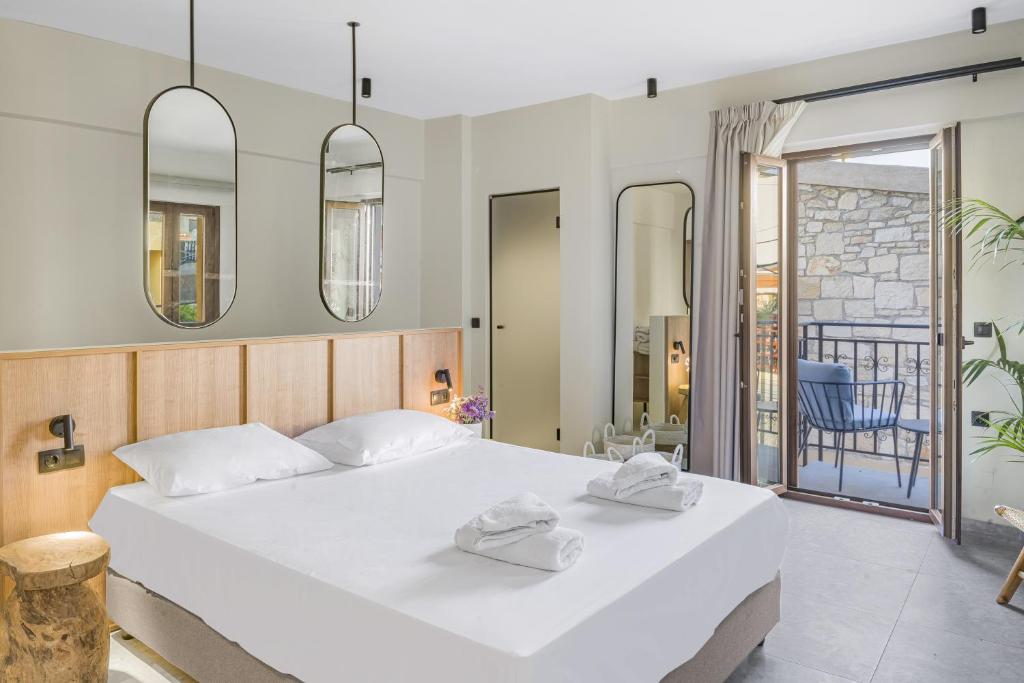 een slaapkamer met een groot wit bed en 2 handdoeken bij Achatis Suites in Chersonissos