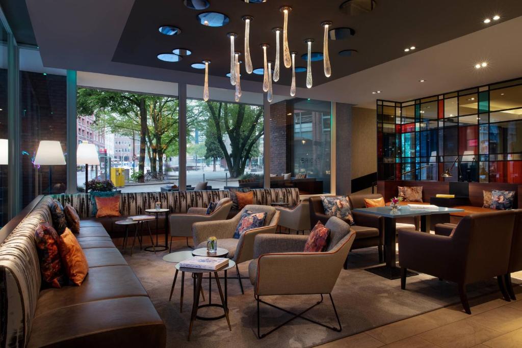 eine Hotellobby mit Sofas, Tischen und einem Kronleuchter in der Unterkunft Renaissance Hamburg Hotel in Hamburg