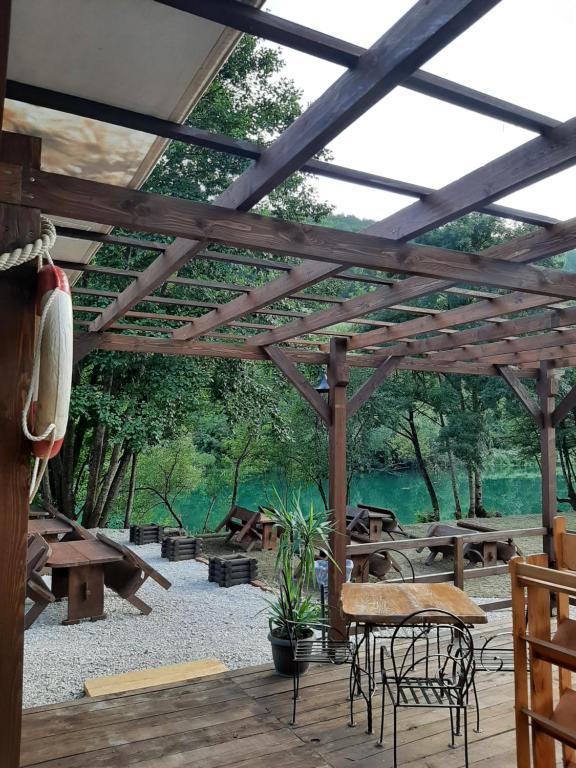 pérgola de madera con mesas de picnic y bancos en Camp Aqualand en Bihać