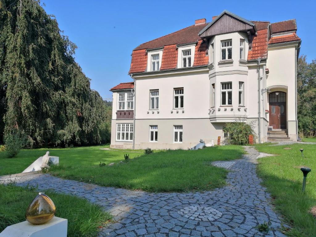 een groot wit huis met een stenen pad voor de deur bij Vila Adelaide in Brtníky