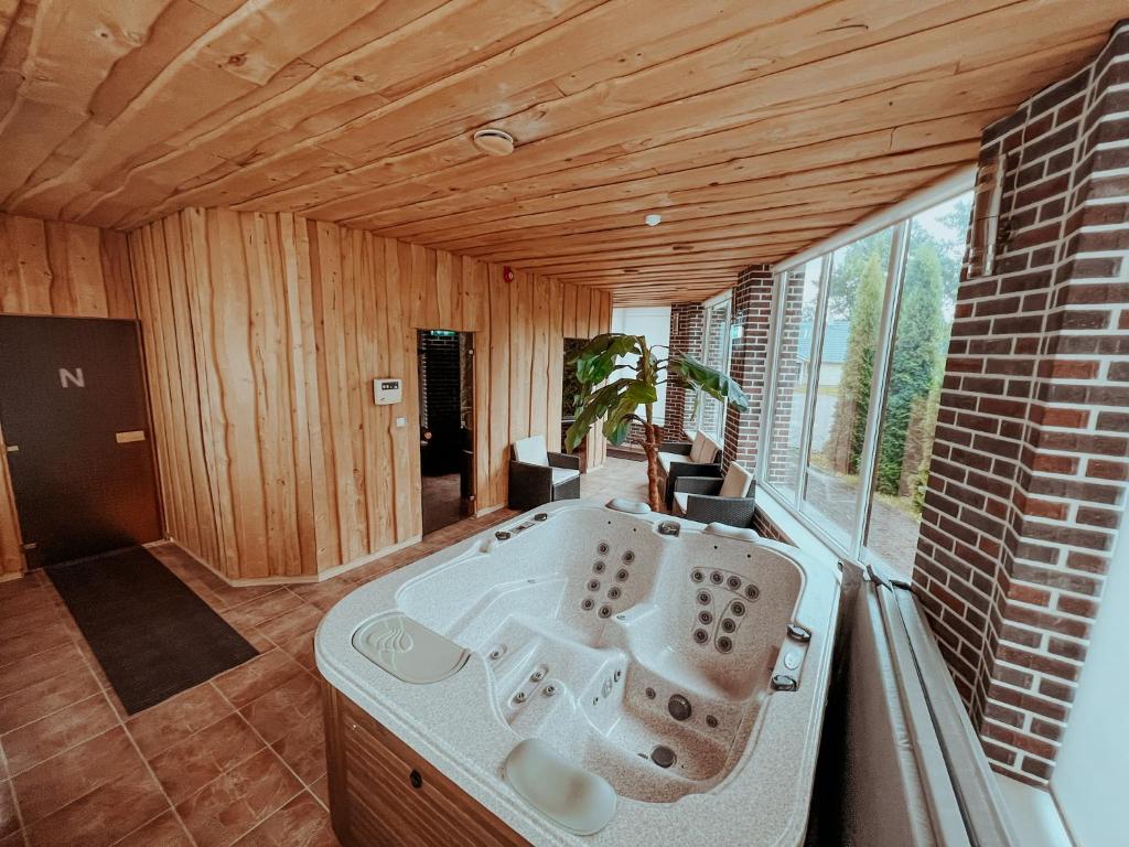 a large bath tub in a room with a large window at Cozy room with kitchen near the lake in Tõrva