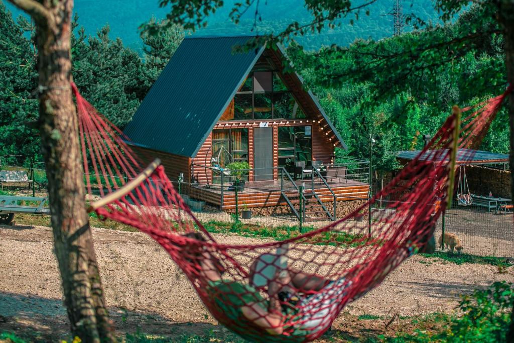 a red hammock in front of a log cabin at Shaori Lake Cottages in Kharistʼvala
