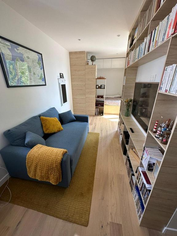 - un salon avec un canapé bleu et des étagères dans l'établissement Studio au calme à deux pas du sacré coeur, à Paris