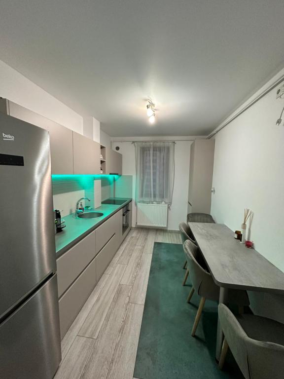 a kitchen with a table and a stainless steel refrigerator at BTA Apartment Park Lake in Cluj-Napoca