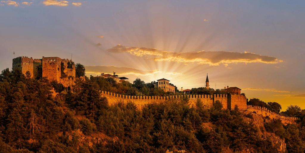 un castillo en una colina con la puesta de sol detrás de él en "Kale Street" Alanya en Alanya