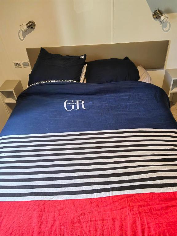ein Bett mit einer blau-weißen gestreiften Decke darauf in der Unterkunft Paisible in Agde