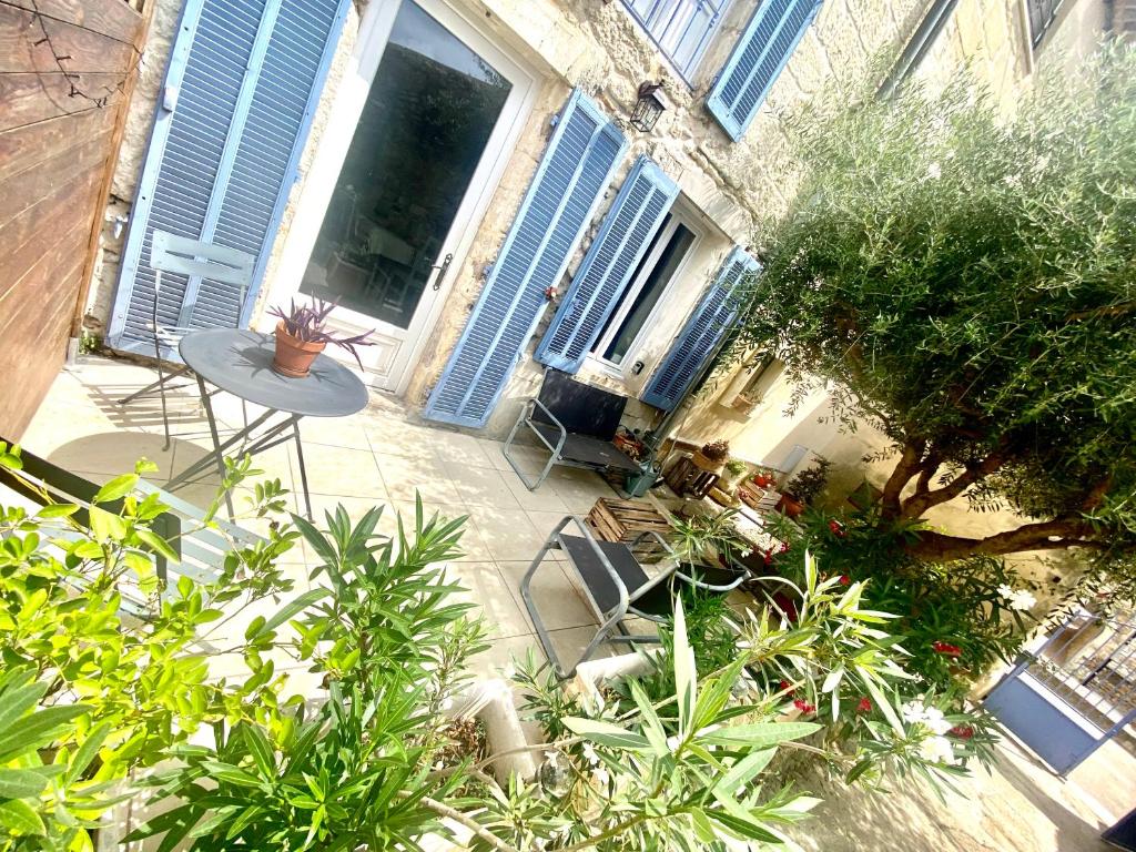 un patio con tavolo, sedie e piante di La Fabuleuse 2etoiles ad Aramon