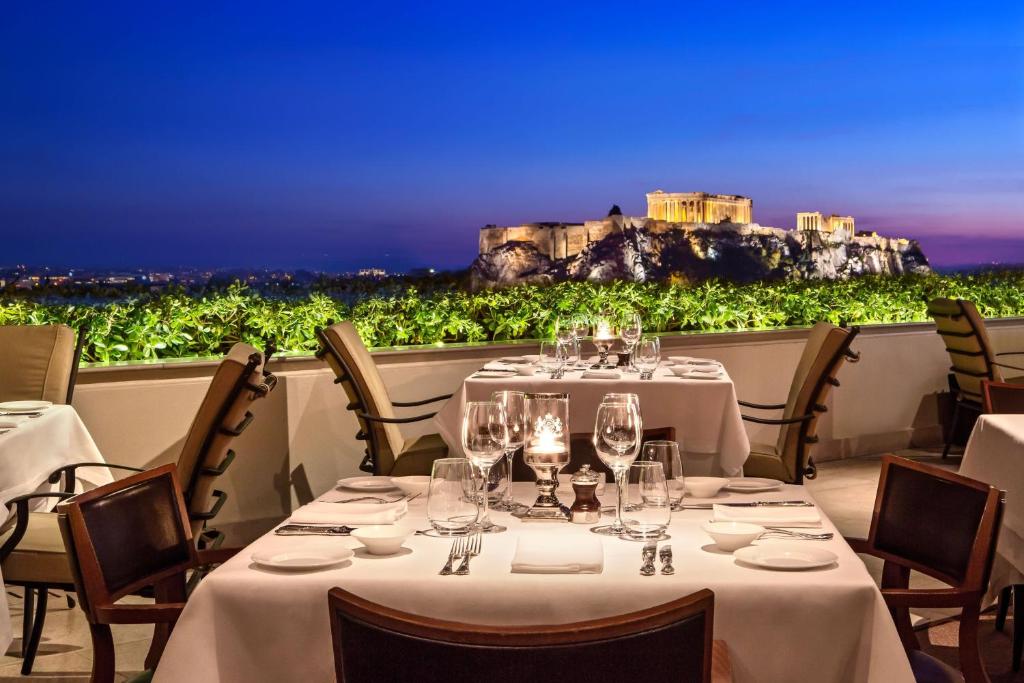 a restaurant with tables and chairs with a view ofhens at Hotel Grande Bretagne, a Luxury Collection Hotel, Athens in Athens