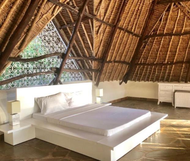 ein Schlafzimmer mit einem Strohdach in der Unterkunft Oasis Retreat in Diani Beach