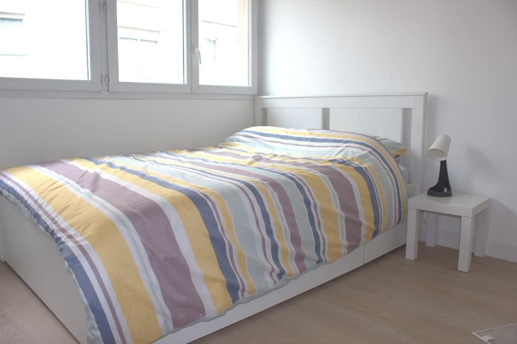 um quarto com uma cama com um cobertor listrado em Studio Paris Sud à côté du métro em Villejuif