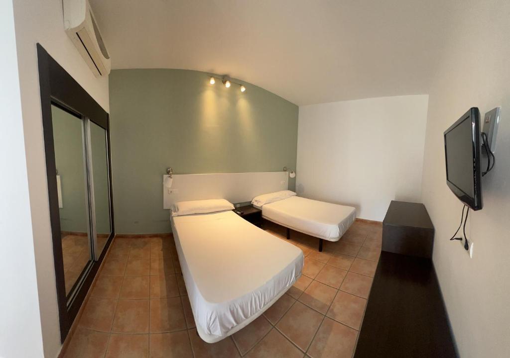 um quarto com 2 camas e uma televisão de ecrã plano em #1 HABITACIÓN DOBLE AYAMONTE em Ayamonte