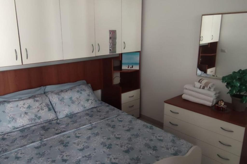 um quarto com uma cama, uma cómoda e um espelho em Appartamento Orchidea em Rimini