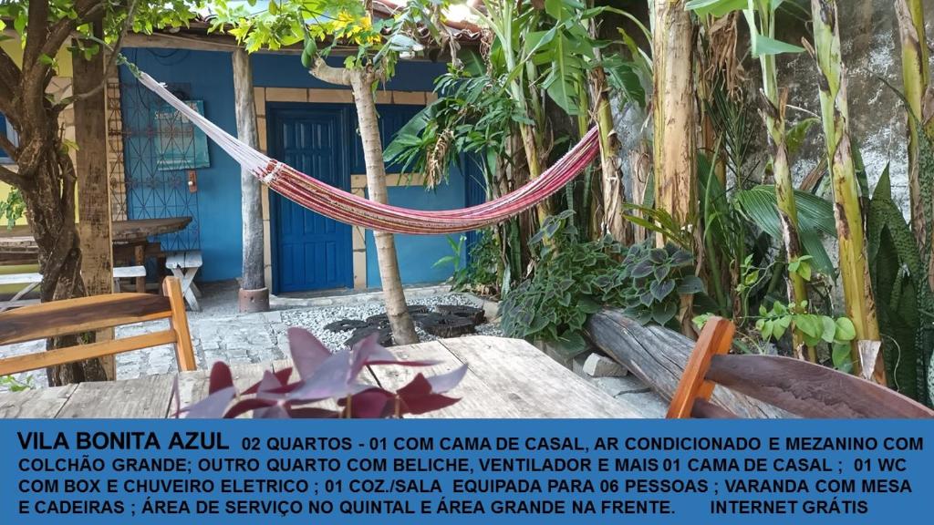 a hammock in front of a building with a sign at Casinhas Vila Bonita Azul in Baía Formosa