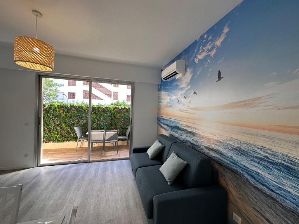 uma sala de estar com um sofá e uma pintura do oceano em Charmant 2 Pièces em Antibes