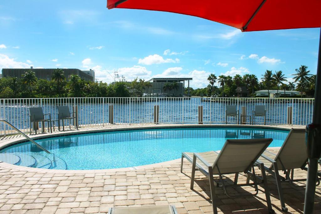 a swimming pool with chairs and a red umbrella at Intracoastal sunsets condo building with 2 beds or 1 bed units private heated pool in Pompano Beach