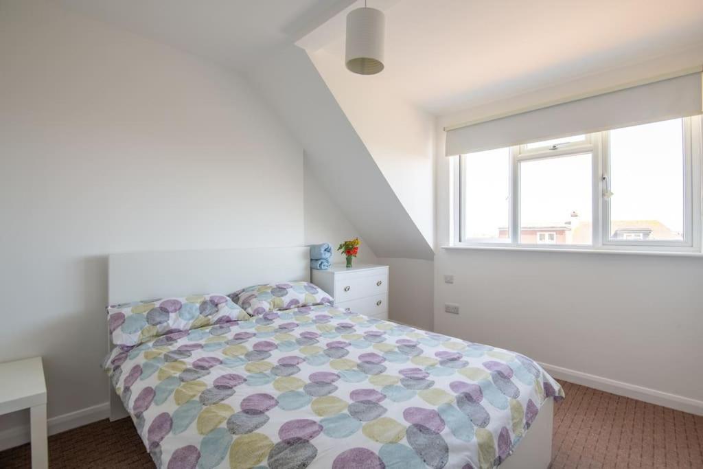 a white bedroom with a bed and a window at Fantastic sea views. One Bedroom flat near the sea in Selsey