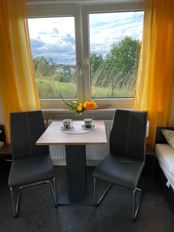 een tafel en 2 stoelen in een kamer met een raam bij FERIENWOHNUNG AM BERG in Marktgraitz