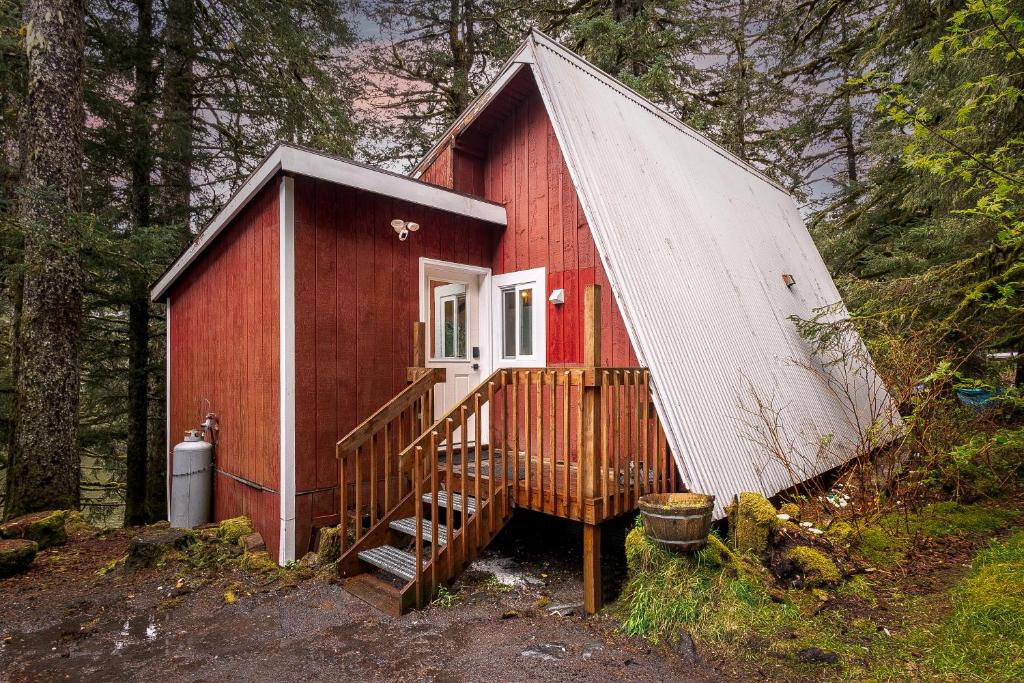 a red cabin with a white roof in the woods at THE SHORELINE CABIN in Kodiak