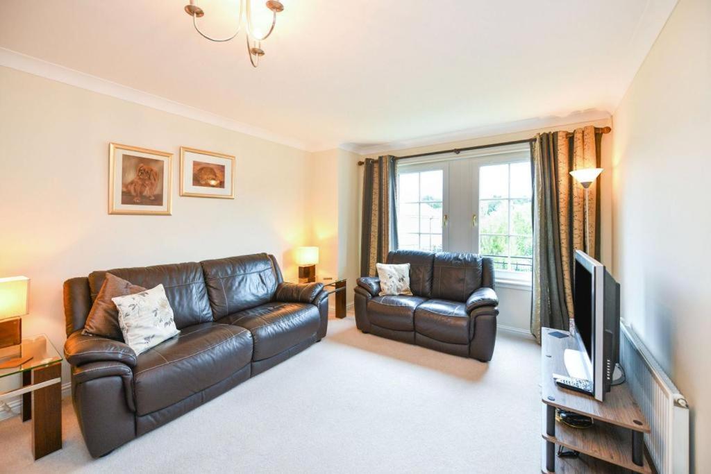 a living room with two leather couches and a television at Fabulous Flat in Stirling