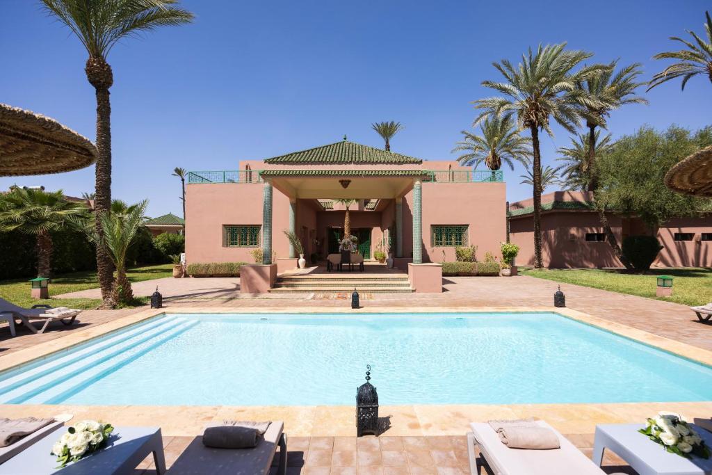 a villa with a swimming pool and palm trees at Domaine Abiad in Marrakesh