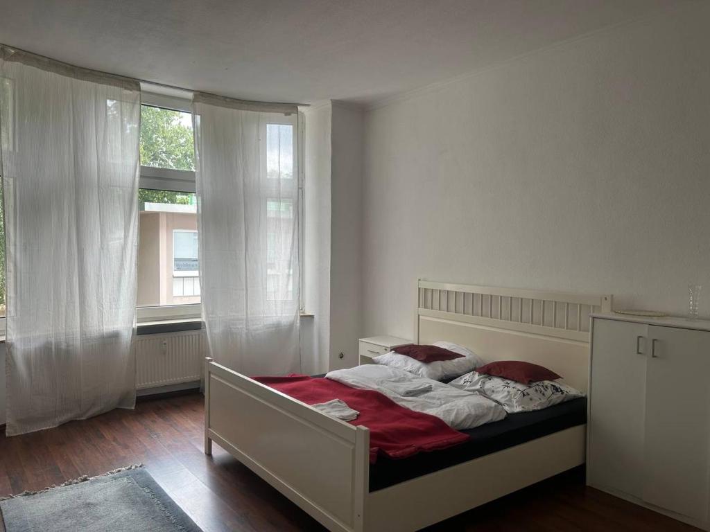 Schlafzimmer mit einem Bett mit roter Bettwäsche und einem Fenster in der Unterkunft 3 Zimmer Mietwohnung nähe HBF in Essen
