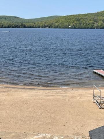 a chair sitting on a beach next to a lake at Condo Lac Archambault 298 in Saint-Donat-de-Montcalm