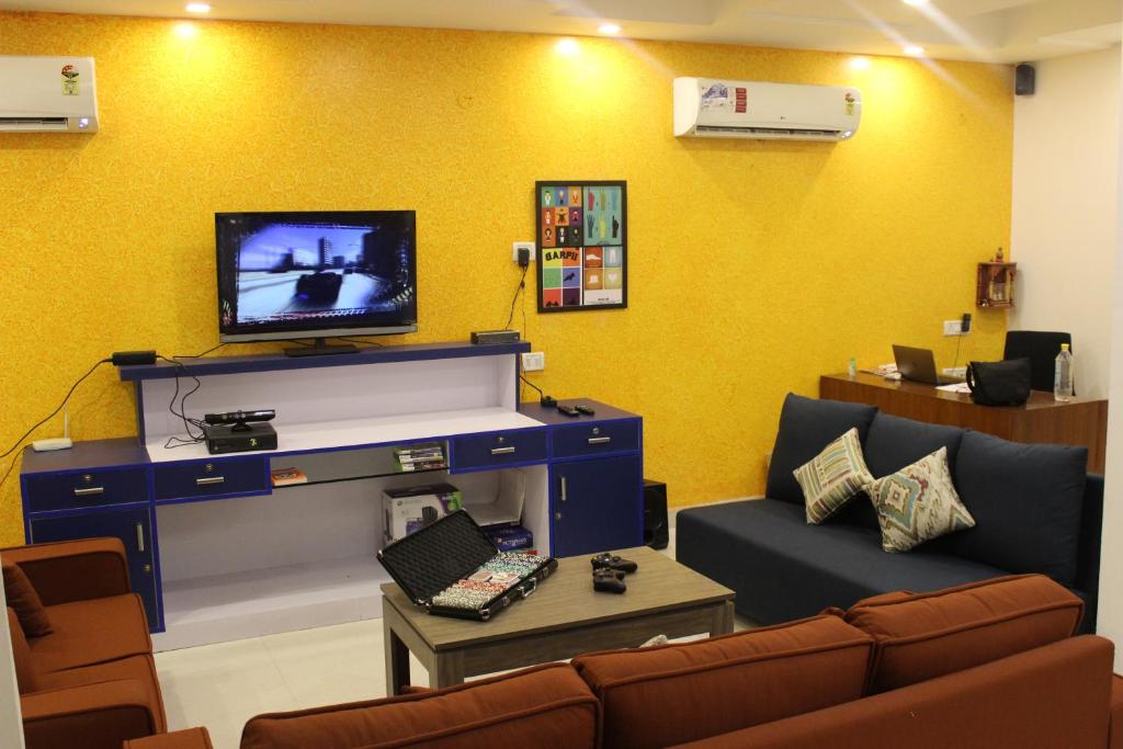 a living room with a couch and a tv on a wall at Joey's Hostel Delhi - 20 mins from Railway Station in New Delhi