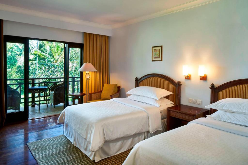 a hotel room with two beds and a balcony at Sheraton Senggigi Beach Resort in Senggigi