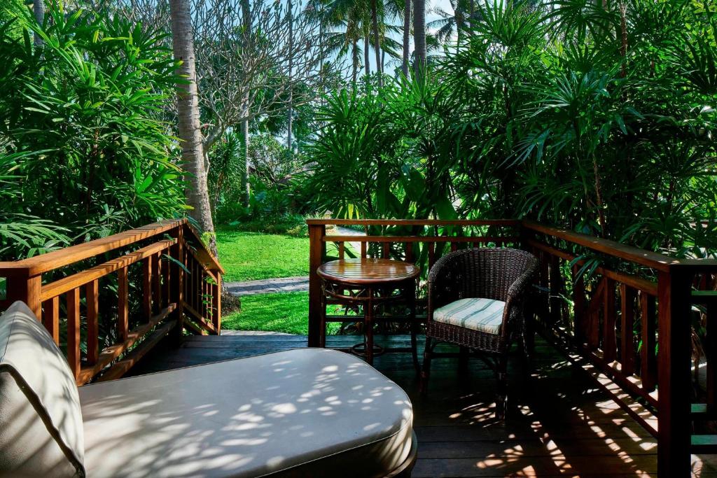 a wooden deck with chairs and a table on it at Sheraton Senggigi Beach Resort in Senggigi