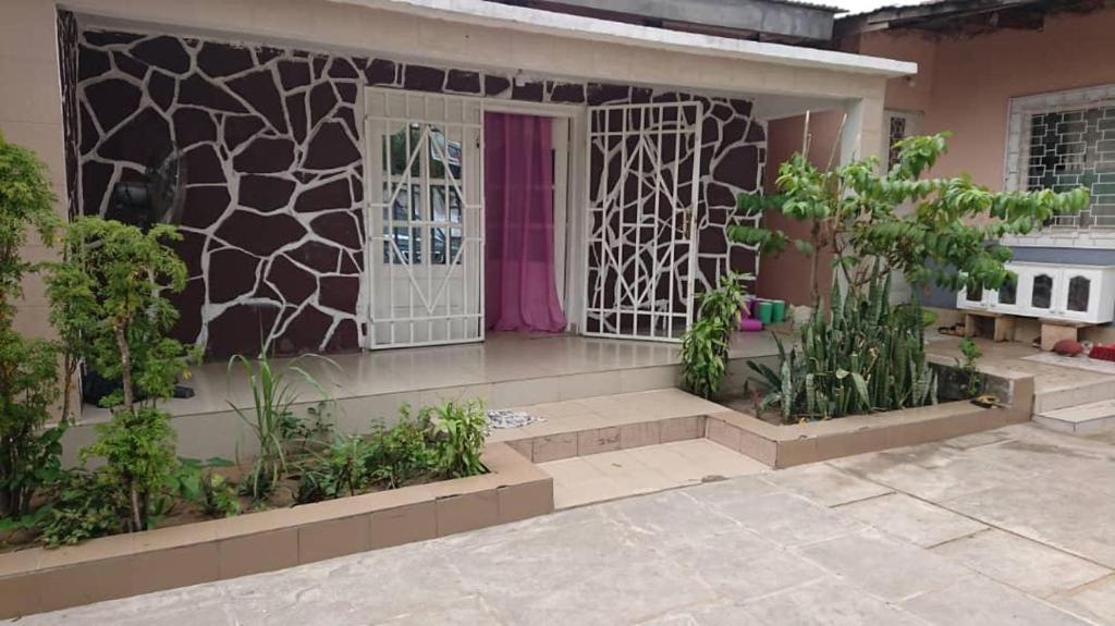 une maison avec une porte rose et quelques plantes dans l'établissement AUBERGE-NGOMSON, à Brazzaville