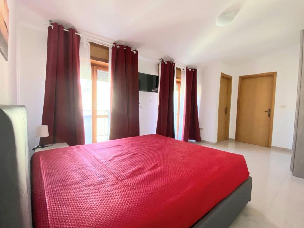 1 dormitorio con cama roja y cortinas rojas en Attico sul Mare, en Vibo Valentia Marina