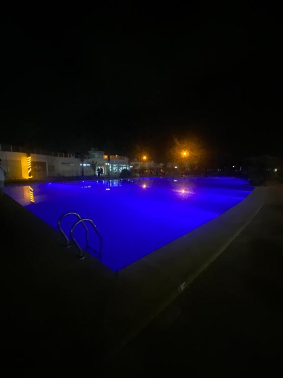 uma piscina à noite com iluminação azul em Villa haut standing dans une résidence fermée em Zaouia Sidi Rahkal