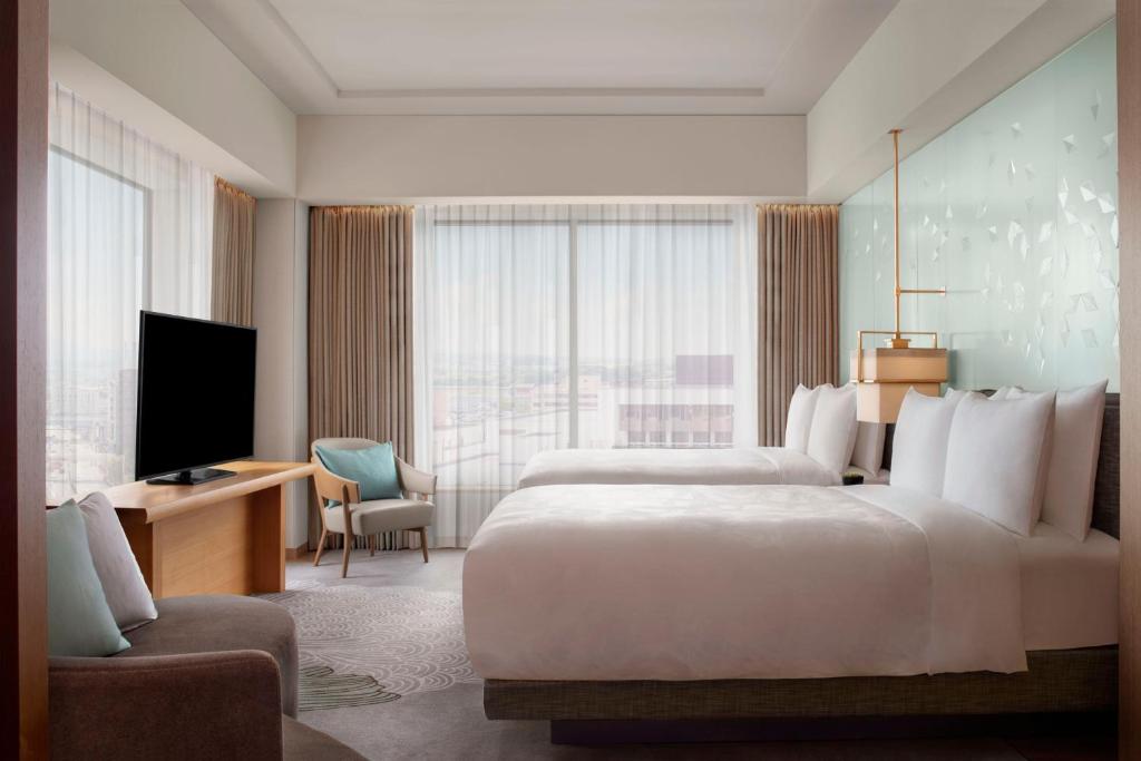a hotel room with two beds and a television at JW Marriott Hotel Nara in Nara
