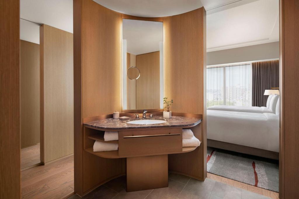 a bathroom with a sink and a mirror and a bed at JW Marriott Hotel Nara in Nara