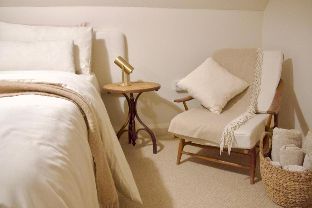 a bedroom with a bed and a chair and a lamp at Oak Tree Cottage in Lincolnshire