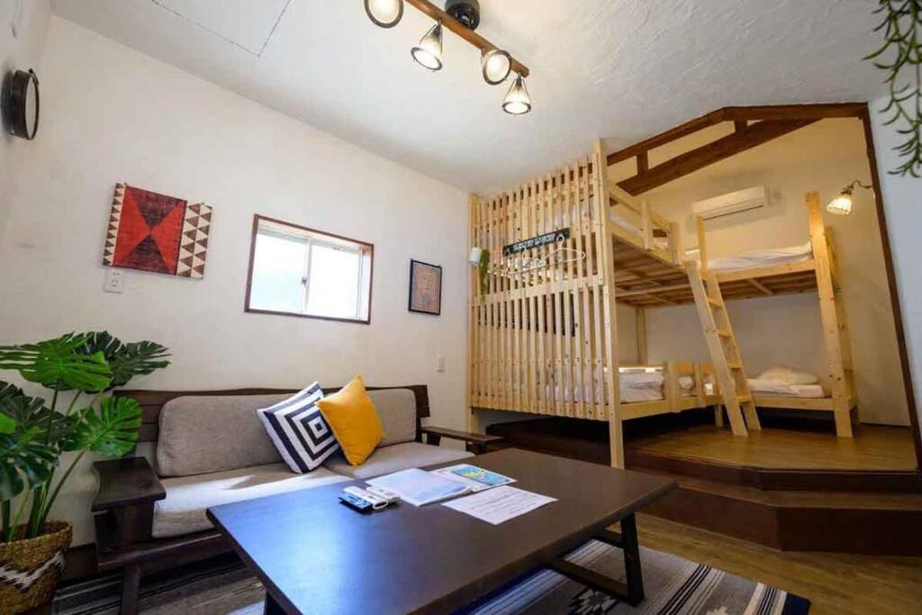 ein Wohnzimmer mit einem Sofa und Etagenbetten in der Unterkunft 日向サーフキャンプ211 in Hyuga